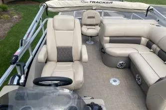 Slide: The Image of 2023 Sun Tracker SportFish 22 DLX pontoon boat interior with beige seating and steering console. - 8