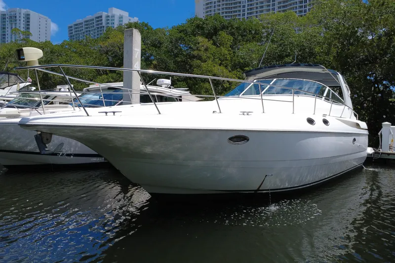 Slide: The Image of 1999 Cruisers Yachts 3870 Esprit docked in a marina, surrounded by trees and buildings. - 13