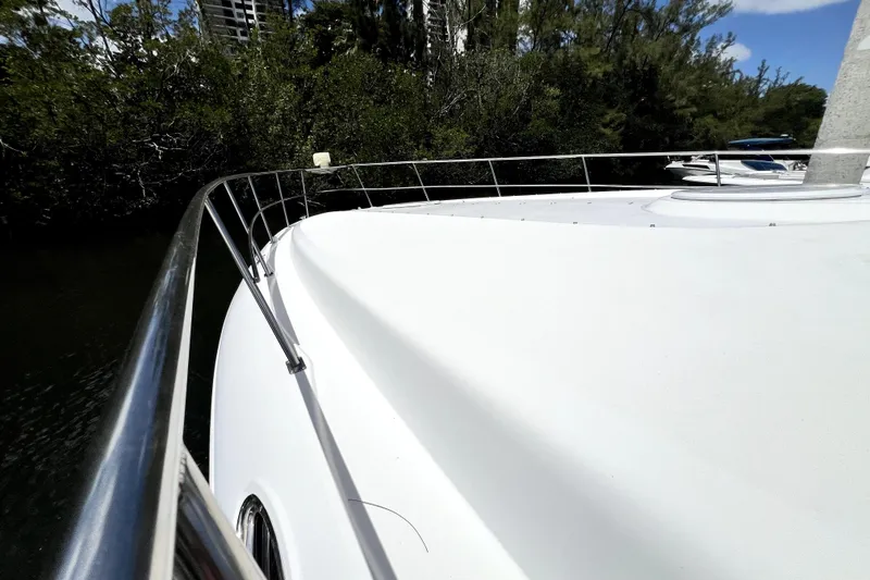 Slide: The Image of 1999 Cruisers Yachts 3870 Esprit boat deck with railing, surrounded by lush greenery. - 36