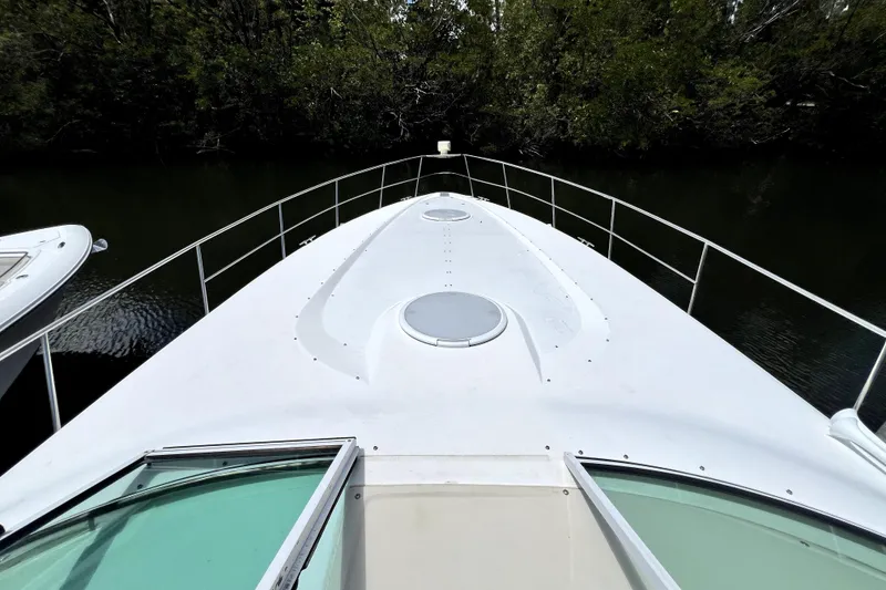 Slide: The Image of 1999 Cruisers Yachts 3870 Esprit bow view, featuring sleek design and railing, docked near greenery. - 38