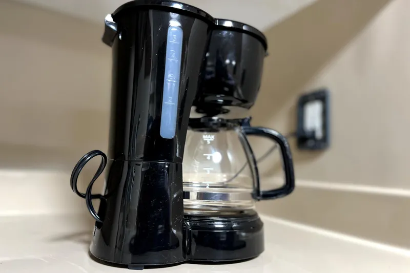 Slide: The Image of Black coffee maker on a beige countertop, featuring a glass carafe. - 69