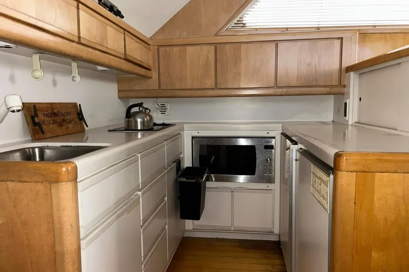 Slide: The Image of Compact kitchen in a 1995 Bertram 43 Convertible yacht with wooden cabinetry and modern appliances. - 10