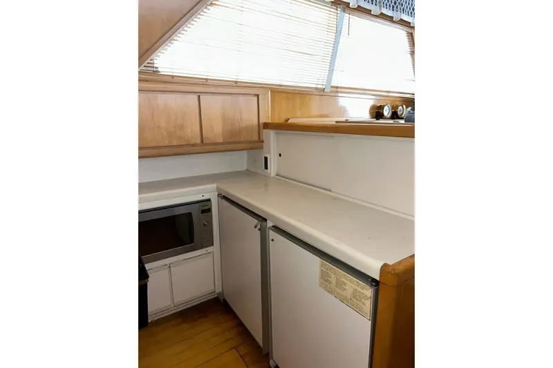 Slide: The Image of Compact kitchen area in a 1995 Bertram 43 Convertible yacht with wooden cabinets. - 11