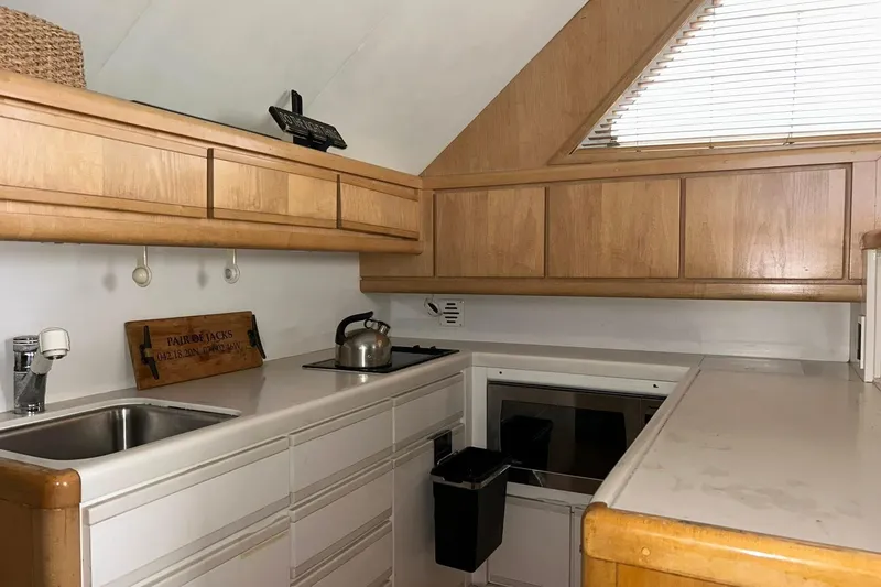 Slide: The Image of Compact kitchen in a 1995 Bertram 43 Convertible yacht with wooden cabinets and modern appliances. - 12