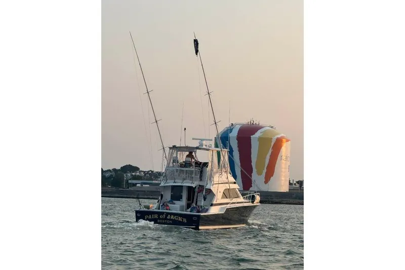 Slide: The Image of 1995 Bertram 43 Convertible boat cruising near colorful waterfront structure. - 3