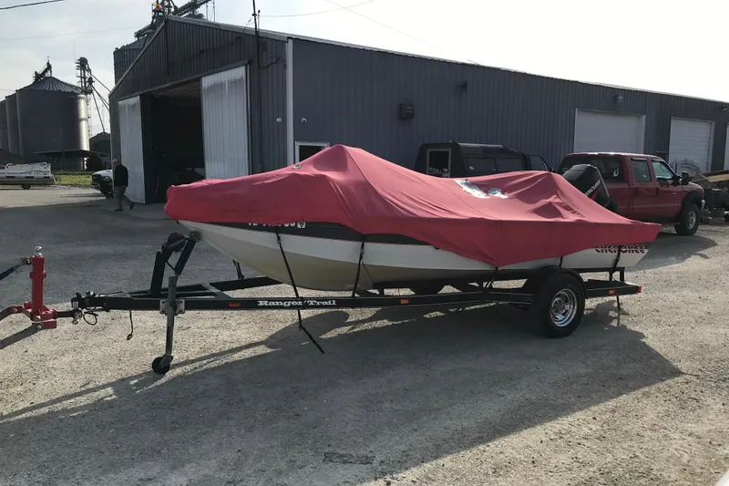 Slide: The Image of 2001 Ranger 217B Cherokee boat with red cover on trailer, parked outside a warehouse. - 6