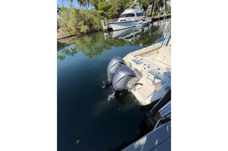 Slide: The Image of 2022 Cobia 320 Center Console with dual Yamaha outboard engines docked in a serene marina. - 3