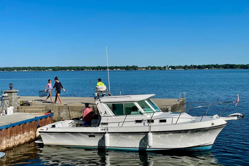 Slide: The Image of 2002 Albin 28 Tournament Express docked by a serene lake under clear blue skies. - 1