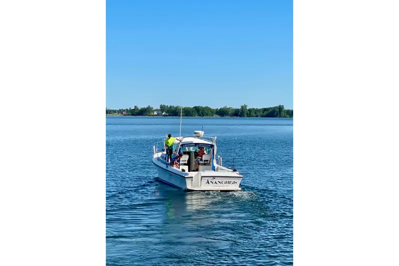 Slide: The Image of 2002 Albin 28 Tournament Express boat cruising on a calm lake under clear blue skies. - 2