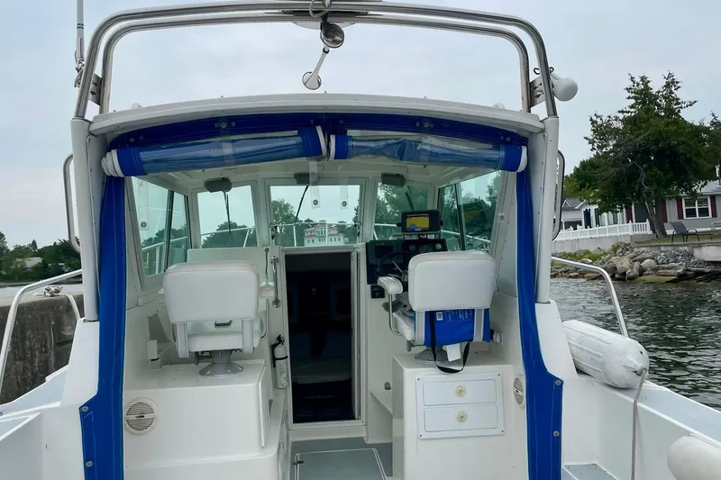 Slide: The Image of 2002 Albin 28 Tournament Express boat interior with helm and seating, docked by the shore. - 4