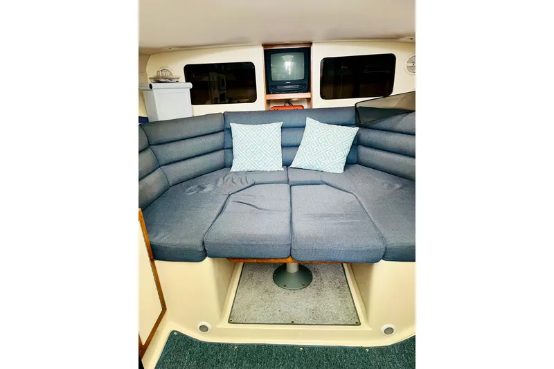 Slide: The Image of Interior of 2002 Albin 28 Tournament Express with blue cushioned seating and decorative pillows. - 7