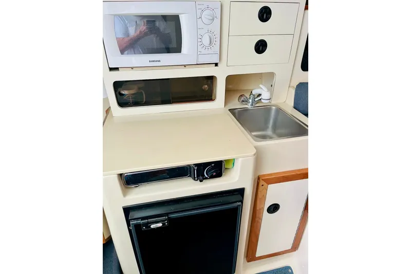 Slide: The Image of Compact kitchen area in a 2002 Albin 28 Tournament Express boat with microwave and sink. - 9