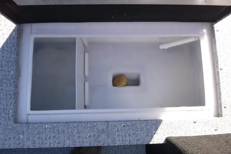 Slide: The Image of 2025 Smoker Craft Lazer 161 boat compartment with a potato and a white pen. - 6