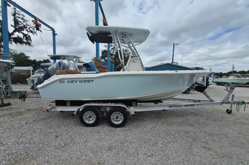 Slide: The Image of 2026 Key West 219 FS boat on trailer, parked outdoors under cloudy sky. - 2
