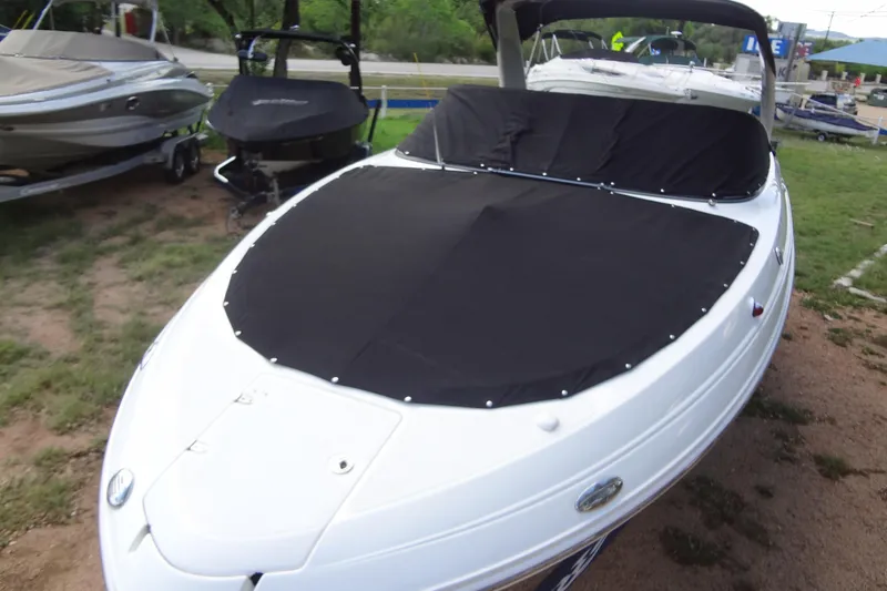 Slide: The Image of 2008 Chaparral 276 SSX boat with black cover, parked on grass. - 43