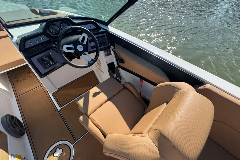 Slide: The Image of 2021 MasterCraft NXT24 boat interior with tan seating and modern dashboard on water. - 11