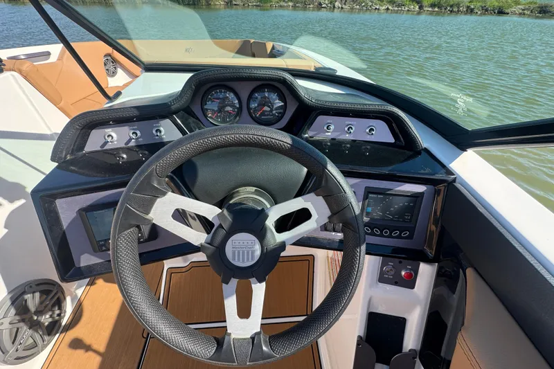 Slide: The Image of 2021 MasterCraft NXT24 boat dashboard with steering wheel and control panel on a sunny day. - 12