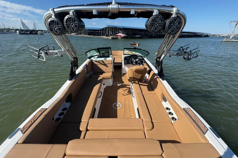Slide: The Image of 2021 MasterCraft NXT24 boat interior with tan seating and wakeboard tower on a lake. - 23