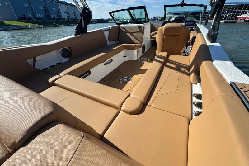 Slide: The Image of 2021 MasterCraft NXT24 boat interior with tan seating, docked by the water. - 24