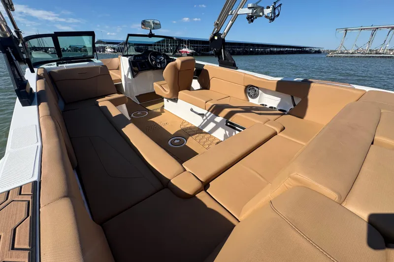 Slide: The Image of 2021 MasterCraft NXT24 boat interior with tan seating, on a sunny day by the water. - 25