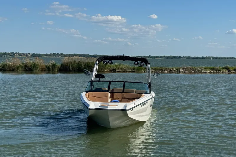 Slide: The Image of 2021 MasterCraft NXT24 boat on a calm lake under a clear blue sky. - 3