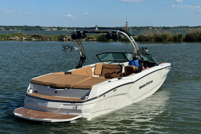 Slide: The Image of 2021 MasterCraft NXT24 boat cruising on a lake with scenic background. - 6