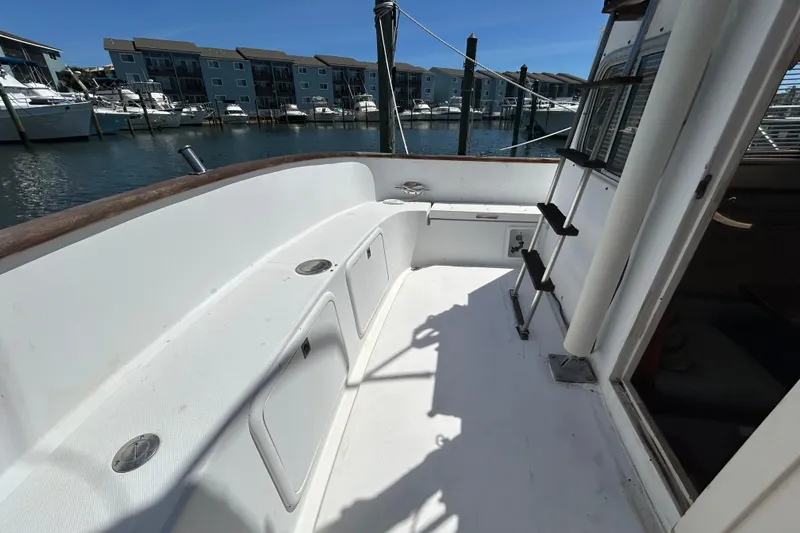 Slide: The Image of 1987 Transpacific Marine Eagle 32 Trawler deck with marina view, featuring storage compartments and ladder. - 10