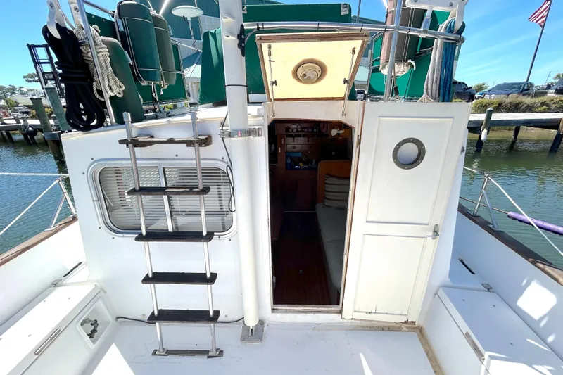 Slide: The Image of 1987 Transpacific Marine Eagle 32 Trawler with open cabin door and ladder, docked by water. - 12