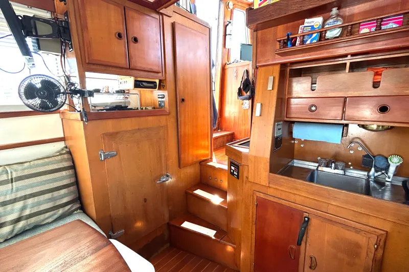 Slide: The Image of Interior of 1987 Transpacific Marine Eagle 32 Trawler with wooden cabinetry and compact kitchen area. - 27