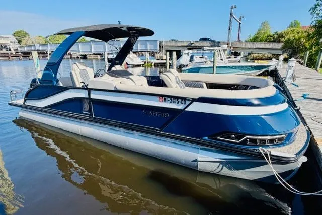 The Image of 2022 Harris Grand Mariner 250 pontoon boat docked in a marina, featuring sleek design and modern amenities. - 0