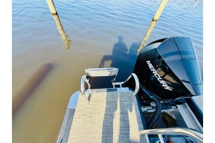 Slide: The Image of 2022 Harris Grand Mariner 250 boat with Mercury engine, docked on calm water. - 13