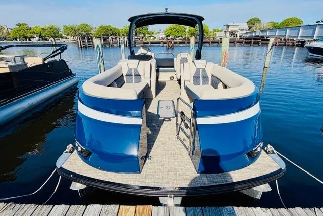 Slide: The Image of 2022 Harris Grand Mariner 250 pontoon boat docked, featuring spacious seating and sleek blue design. - 2