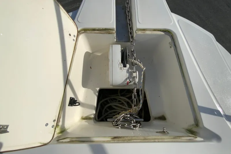 Slide: The Image of Anchor storage compartment on a 2000 Boston Whaler 26 Outrage boat, featuring chain and rope. - 25