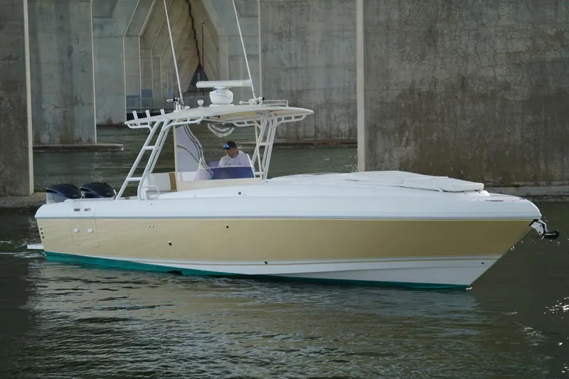 The Image of 2003 Intrepid 370 Cuddy boat cruising under a bridge, featuring sleek design and dual engines. - 0