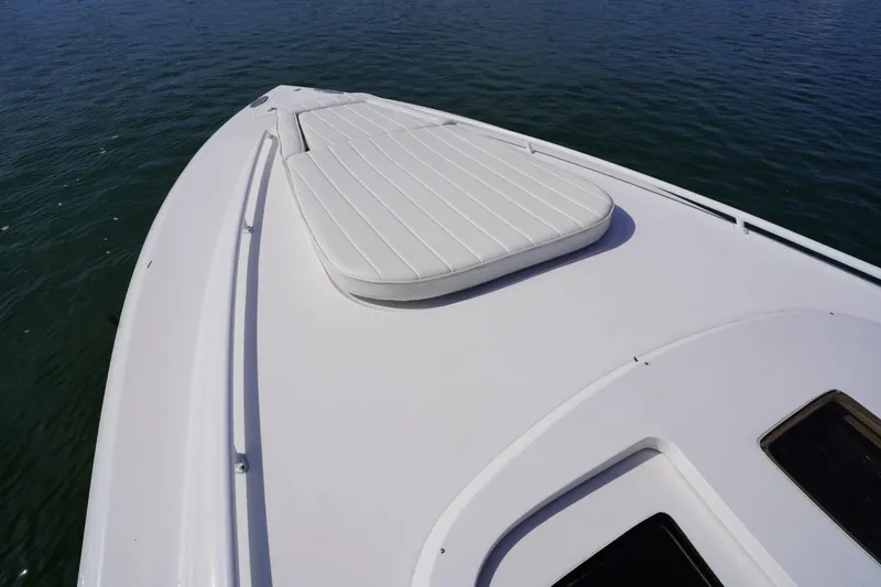 Slide: The Image of 2003 Intrepid 370 Cuddy boat deck with cushioned seating, on calm water. - 21