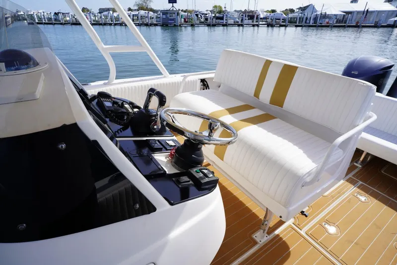 Slide: The Image of 2003 Intrepid 370 Cuddy boat cockpit with steering wheel and white cushioned seating. - 25