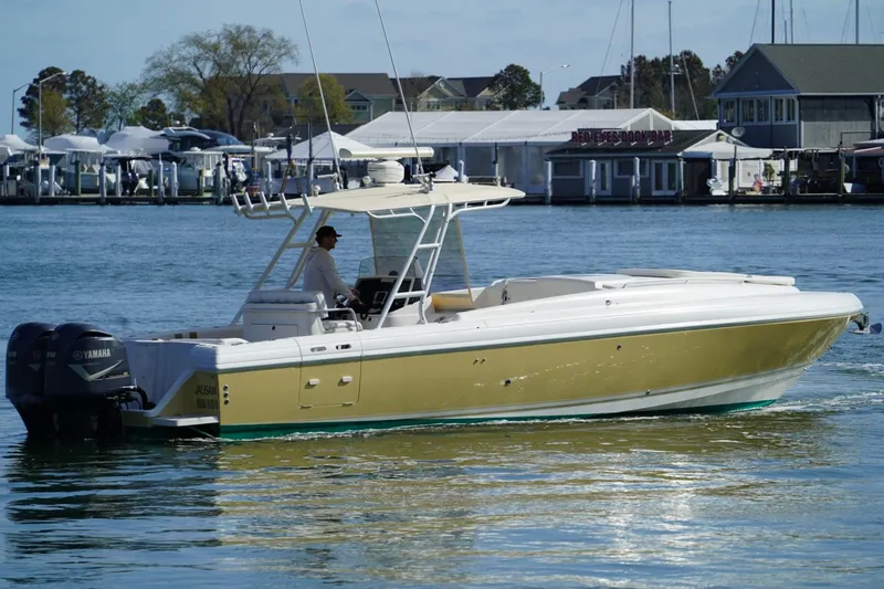 Slide: The Image of 2003 Intrepid 370 Cuddy boat cruising on a calm waterfront with marina backdrop. - 4