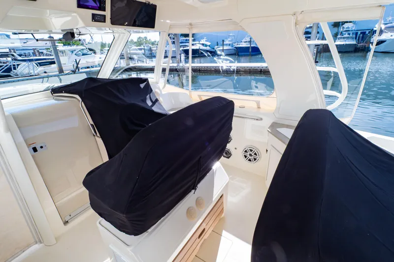 Slide: The Image of 2019 Boston Whaler 350 Realm interior with covered seats, docked at marina. - 112