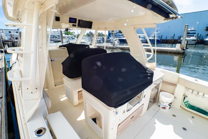 Slide: The Image of 2019 Boston Whaler 350 Realm boat interior at marina, featuring covered seating and helm. - 114