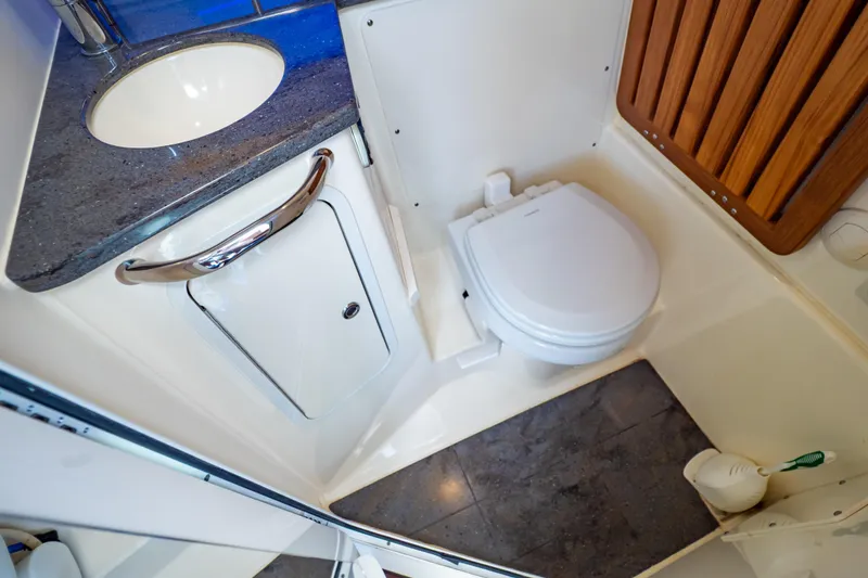 Slide: The Image of 2019 Boston Whaler 350 Realm bathroom with sink, toilet, and wooden accents. - 22