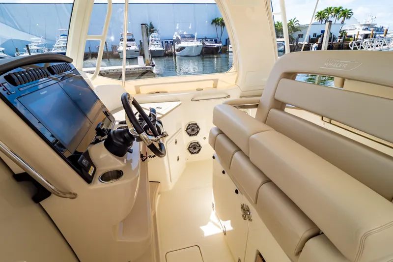Slide: The Image of 2019 Boston Whaler 350 Realm interior with helm and seating, docked at marina. - 3