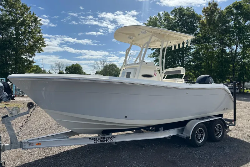 The Image of 2022 Cobia 220 Center Console boat on trailer, parked outdoors under clear sky. - 0