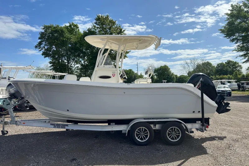 Slide: The Image of 2022 Cobia 220 Center Console boat on trailer, parked outdoors under blue sky. - 1