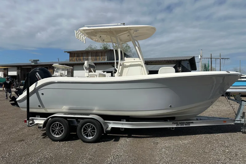 Slide: The Image of 2022 Cobia 220 Center Console boat on trailer, parked outdoors under cloudy sky. - 6