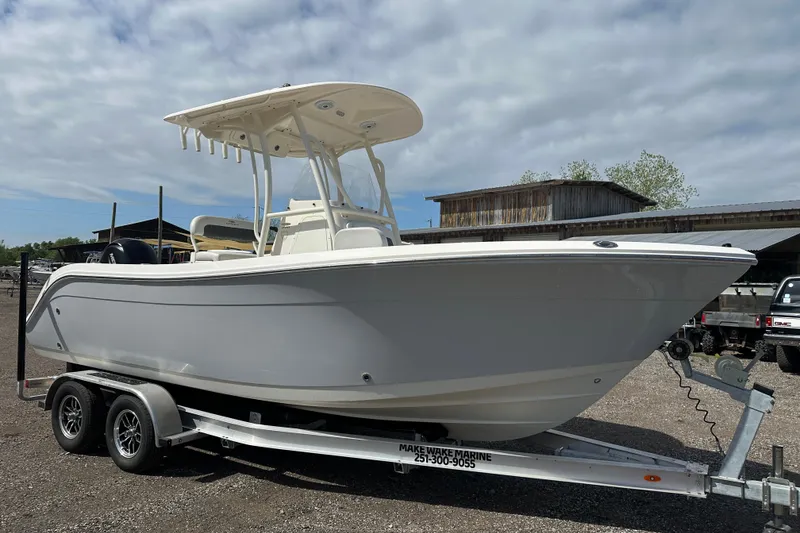 Slide: The Image of 2022 Cobia 220 Center Console boat on trailer, parked outdoors under cloudy sky. - 7