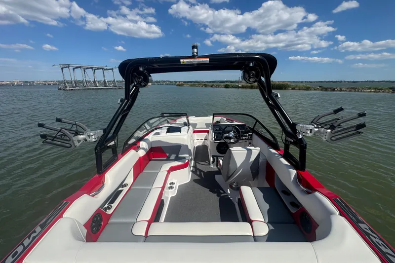 Slide: The Image of 2017 Moomba Helix boat interior with seating, steering wheel, and wakeboard racks on a sunny lake. - 23