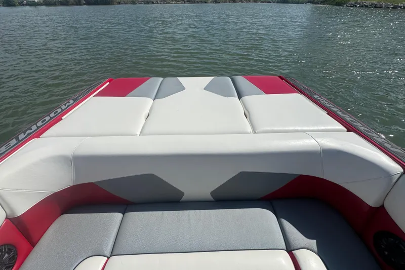 Slide: The Image of 2017 Moomba Helix boat interior with red and gray seating on a lake. - 27