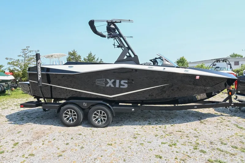 The Image of 2023 Axis T220 boat on trailer, sleek black design, parked outdoors. - 0