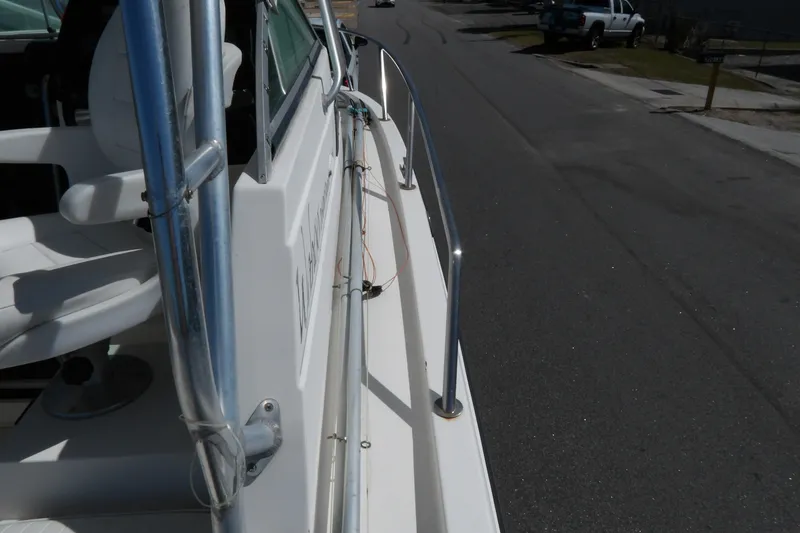 Slide: The Image of 1993 Wahoo 2600 boat parked on a street, showing side railing and seating. - 25