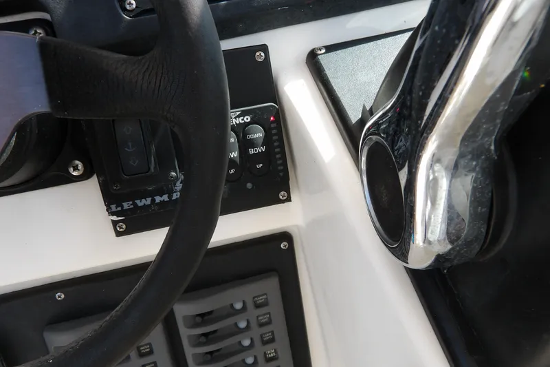 Slide: The Image of Close-up of 1993 Wahoo 2600 boat controls, featuring steering wheel and trim tab switches. - 13